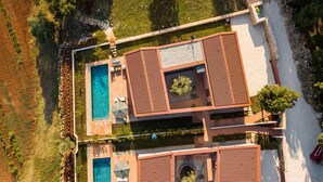 Vista aérea de um resort com piscina, espreguiçadeiras e um jardim bem cuidado.