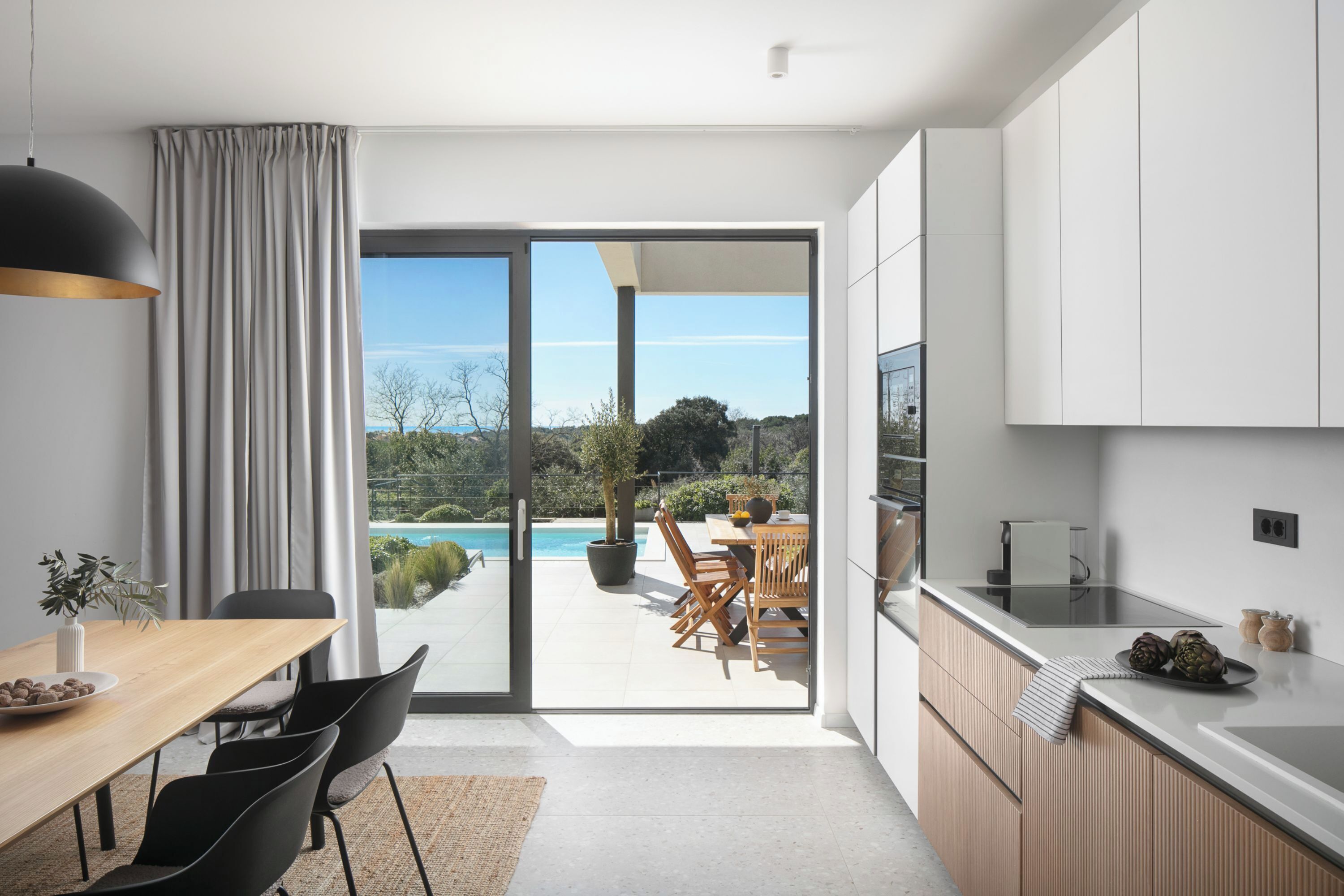 Una cucina moderna con una porta scorrevole in vetro che dà su un patio con piscina.