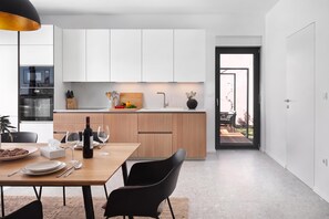 Una cocina moderna con armarios blancos, una mesa de comedor de madera y vistas al exterior.