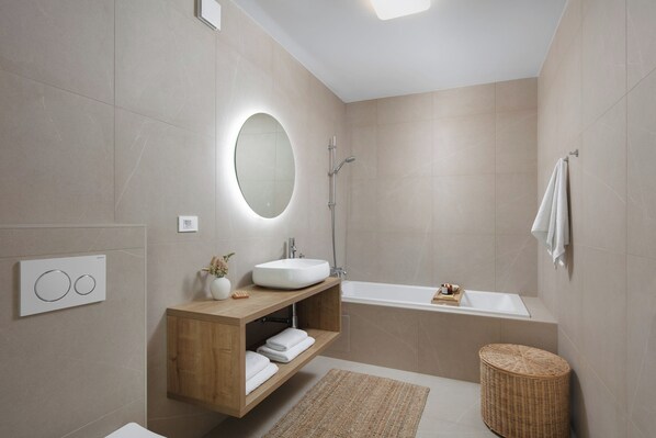 Un baño moderno con una bañera independiente, un tocador con espejo y una ducha.