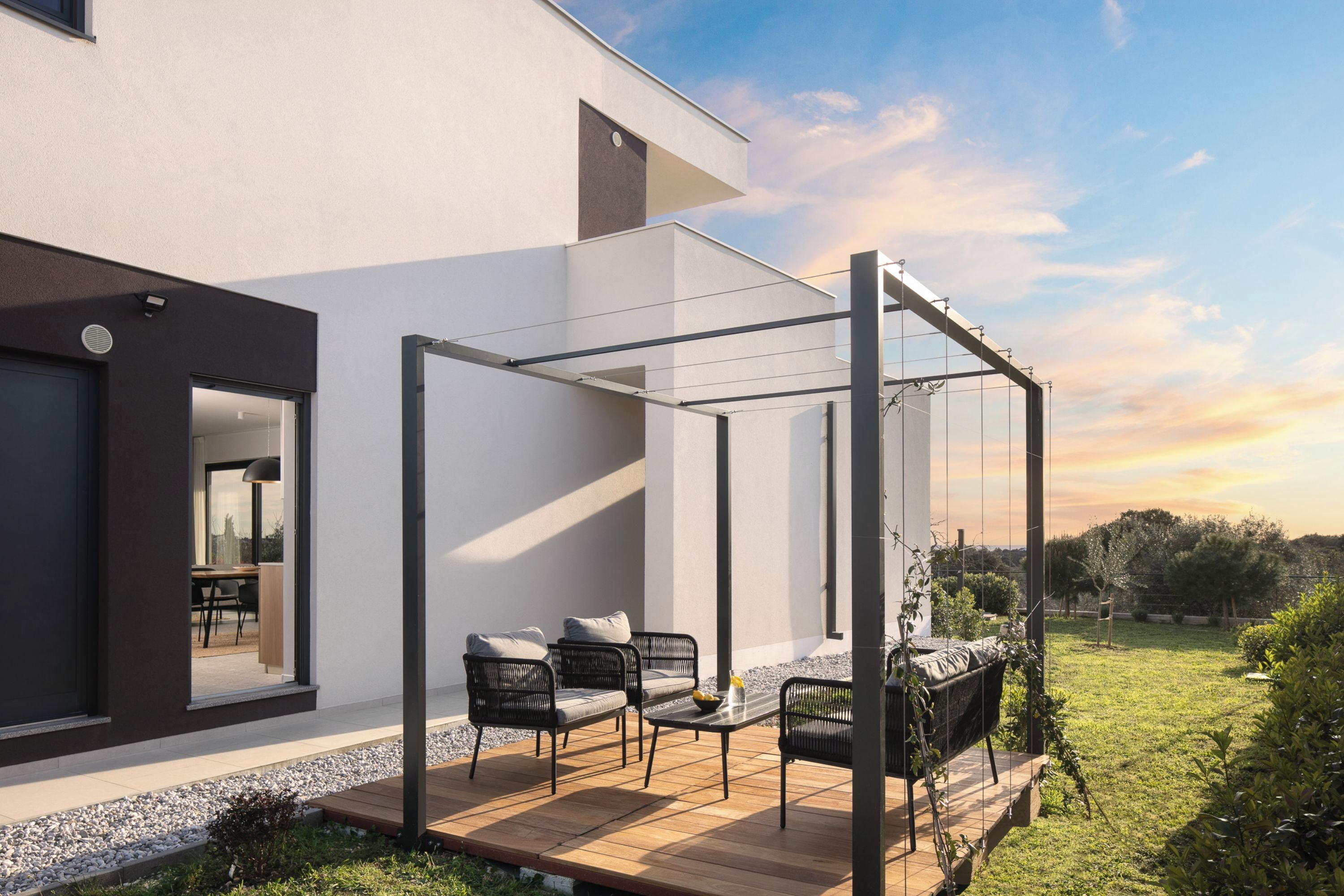 A modern outdoor patio with a pergola, seating area, and a view of the surrounding landscape.
