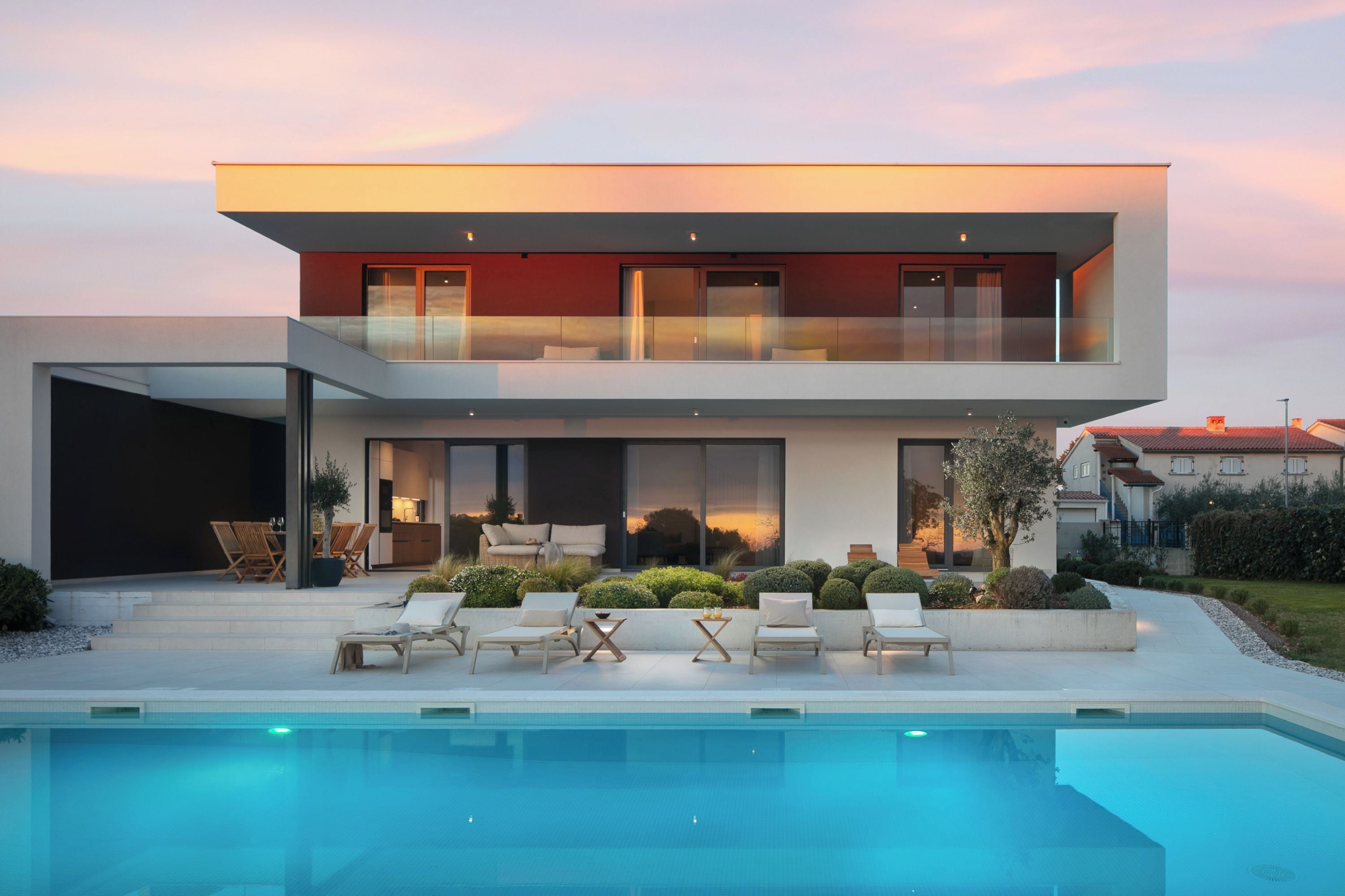 Een modern huis met twee verdiepingen, een zwembad, terras en tuin.