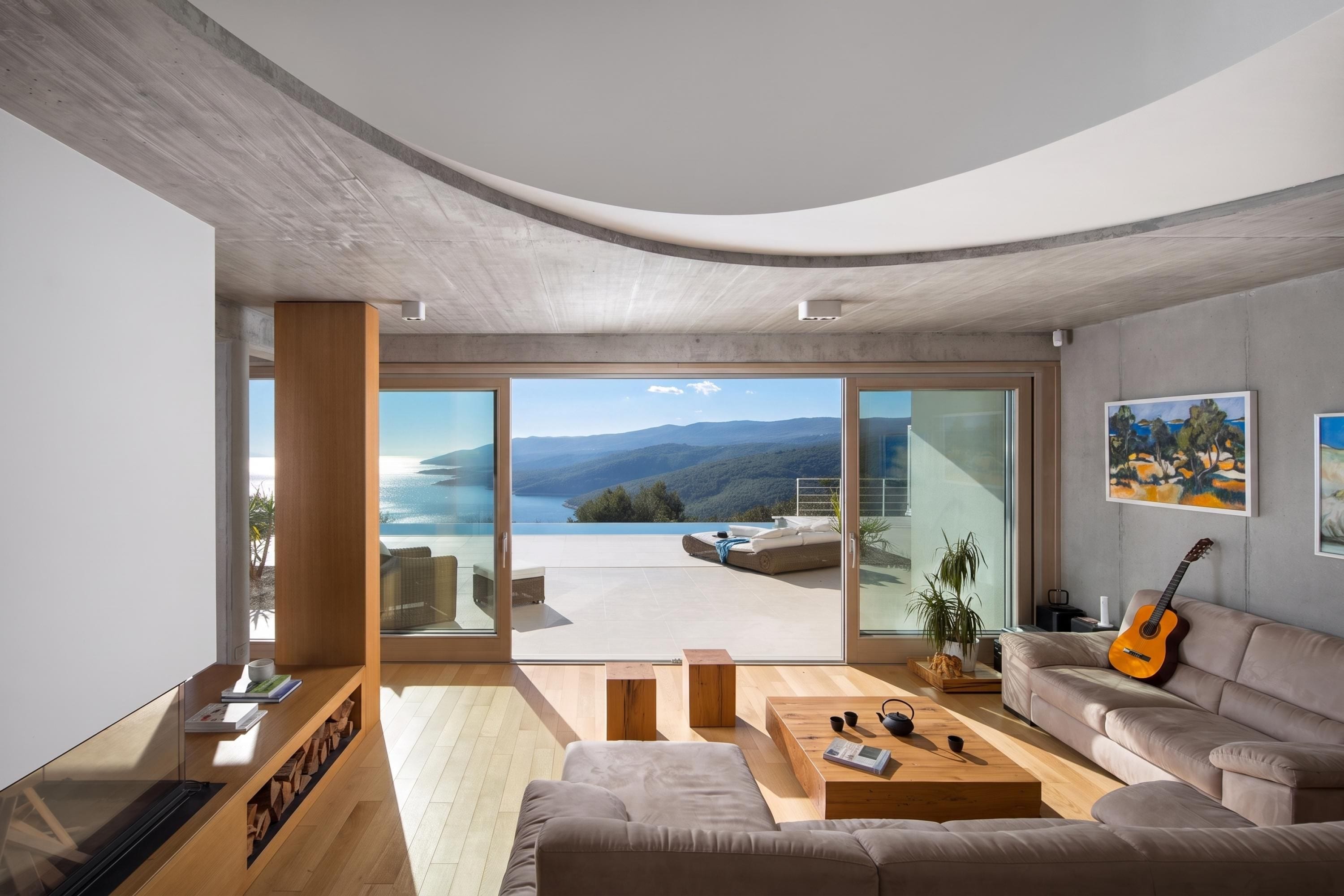 A modern living room with a large sliding glass door leading to a balcony with a scenic view.