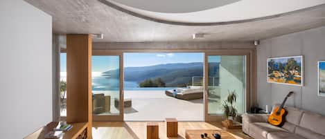 A modern living room with a large sliding glass door leading to a balcony with a scenic view.