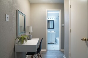 A hallway with a white door leading to a bathroom with a vanity and a mirror. - The Palm Flats 11! Zoo! Museums! Medical Center! (Houston)