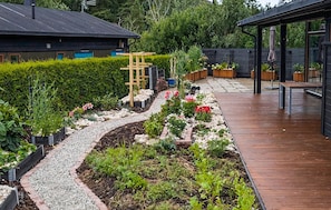 A garden with a gravel path, various plants, a wooden trellis, and a wooden deck. - 2 bedroom stunning home in Larkollen (Larkollen)