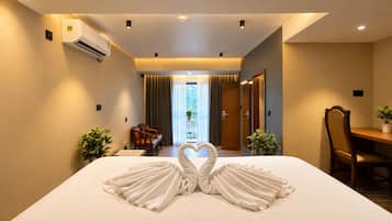 Habitación de hotel con cama, escritorio, silla, mesa de comedor y vistas al exterior.