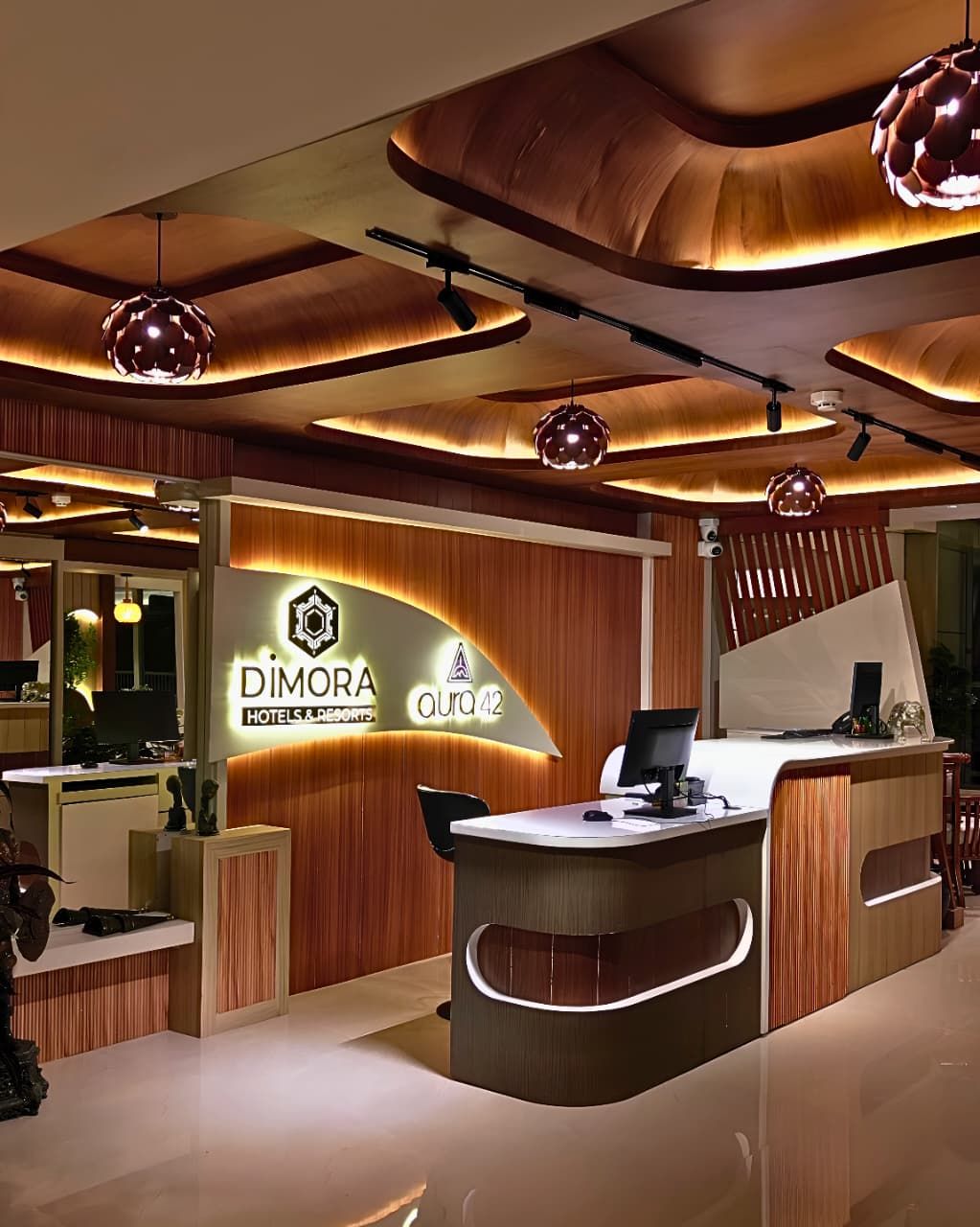 Ein Empfangsbereich im modernen Design, mit einem Holzbüro, einem digitalen Bildschirm und einem Schild mit der Aufschrift 'DIMORA HOTELS & RESORTS aura 42'.
