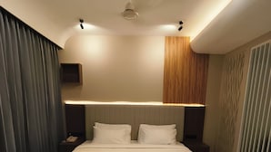 A modern hotel room with a large bed, a ceiling fan, recessed lighting, and a wall-mounted telephone. - AURA 42 BY DIMORA (Devikolam)