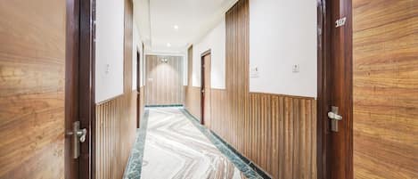 A hallway with wooden paneling and marble flooring, leading to doors numbered 107.