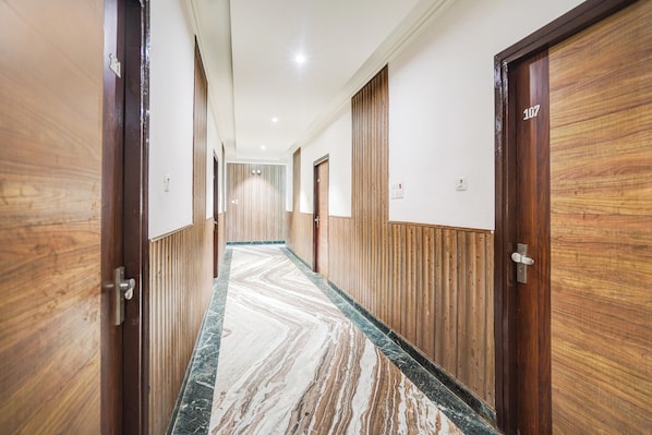 A hallway with wooden paneling and marble flooring, leading to doors numbered 107. - Collection O Civil Lines Rudrapur (Rudrapur)