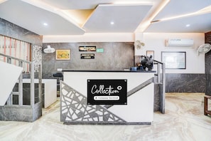 A reception desk with a sign indicating a check-out time of 12 noon and a company-serviced label. - Collection O Civil Lines Rudrapur (Rudrapur)