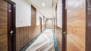 Un pasillo de hotel con paneles de madera, suelo de mármol y puertas numeradas 101, 202 y 303.