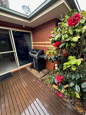 A patio with a barbecue grill, a sliding glass door, and a brick wall. - Beach retreat.
Cosy two bedroom villa, with every box ticked opposite the beach. (Seaholme)