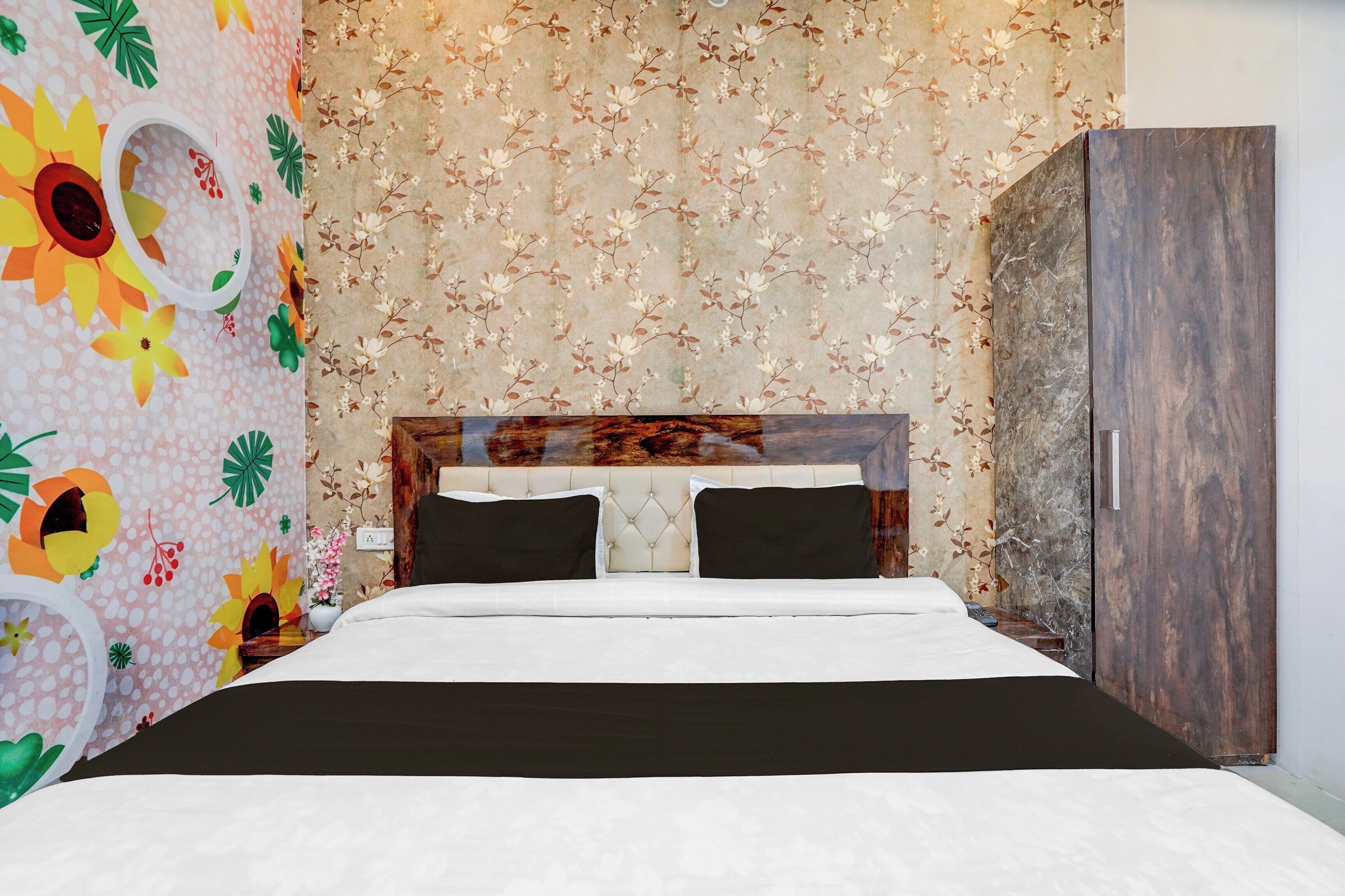 A bedroom with a bed, a wardrobe, and floral wallpaper.