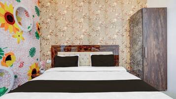 A bedroom with a bed, a wardrobe, and floral wallpaper.