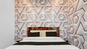 Ein modernes Schlafzimmer mit Wand in geometrischem Muster, einem gesteppten Kopfteil und einem ordentlich bezogenen Bett.