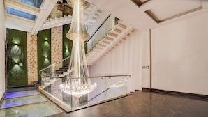 Ein großzügiger Innenraum mit einer imposanten Treppe, einem Chandelier und einer Glasreling.