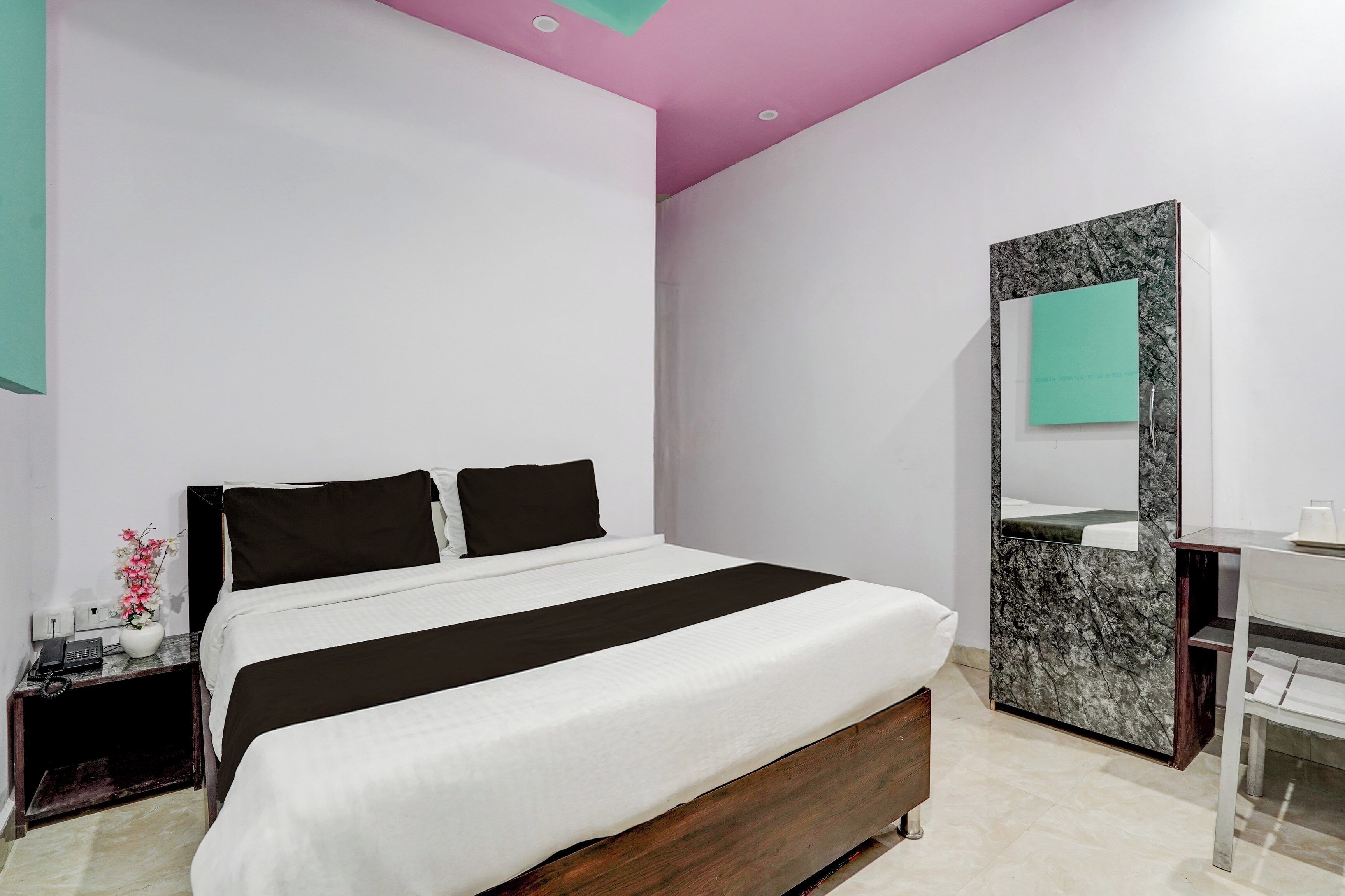 Un dormitorio moderno con cama, mesita de noche, espejo y tocador de baño.