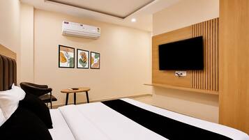 A hotel room with a bed, a TV mounted on the wall, a small table, and two framed artworks.