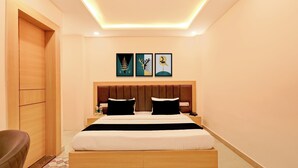 A hotel room with a bed, a headboard, a nightstand, a chair, and artwork on the wall. - Collection O Rudrapur Bus Station (Rudrapur)