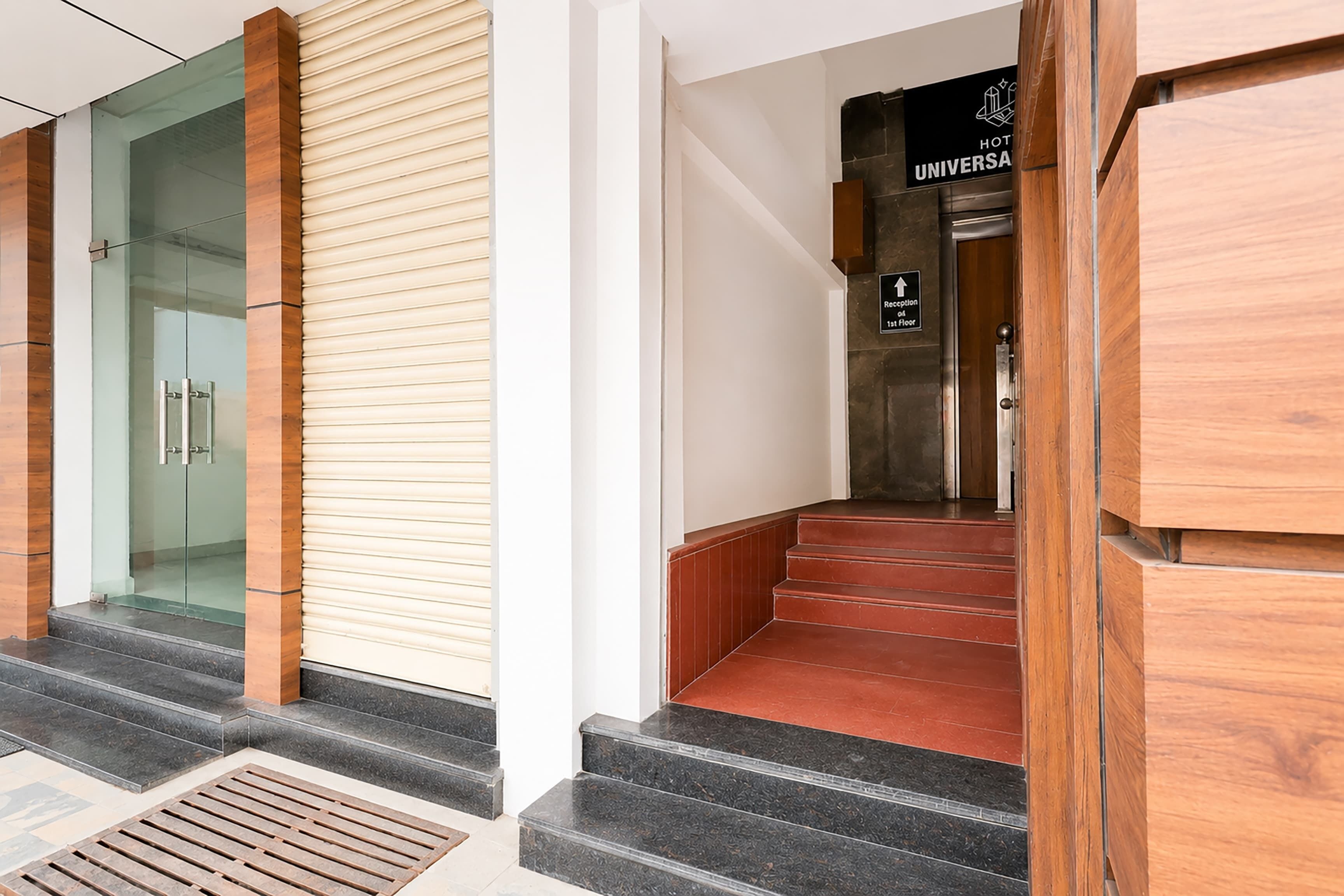 Zona de recepción de un hotel, con un mostrador de recepción, un letrero que indica que la recepción está en el primer piso y una escalera que conduce a los pisos superiores.