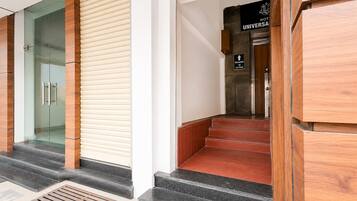 Zona de recepción de un hotel, con un mostrador de recepción, un letrero que indica que la recepción está en el primer piso y una escalera que conduce a los pisos superiores.