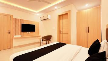 Una habitación de hotel moderna con cama, televisor montado en la pared, una silla y un armario.