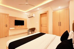 Una habitación de hotel moderna con cama, televisor montado en la pared, una silla y un armario.