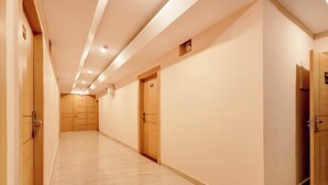 A long, narrow hallway with wooden doors and a tiled floor. - Collection O Rudrapur Bus Station (Rudrapur)