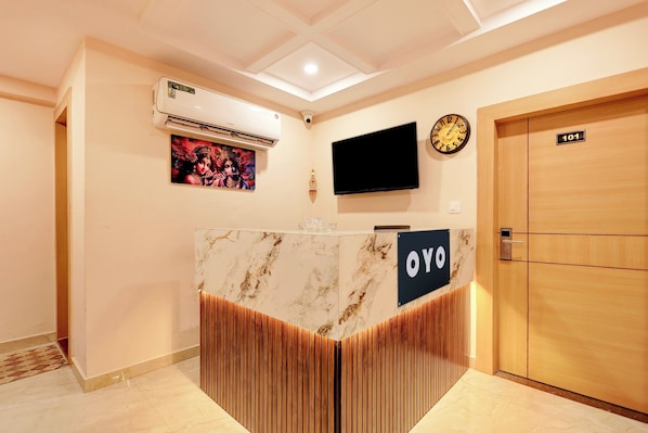 A reception desk with a marble top and a wooden accent, a clock, a television, and a door labeled '101'.