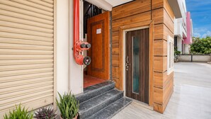 A modern building entrance with a wooden door, a red fire hose, and a potted plant. - Collection O Rudrapur Bus Station (Rudrapur)
