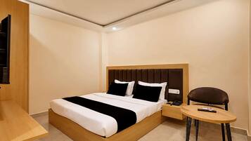 Habitación de hotel moderna con una cama de madera, una mesita de noche, una silla y un escritorio pequeño.