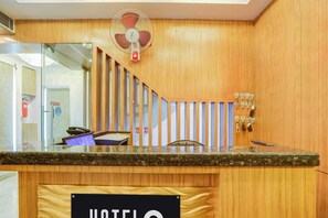 Un mostrador de recepción con acabado de madera, un ventilador encima y un cartel con la palabra 'HOTEL' debajo.