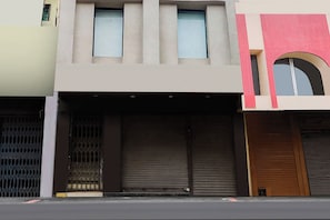 Un edificio con persianas cerradas, una reja metálica y una puerta marrón.