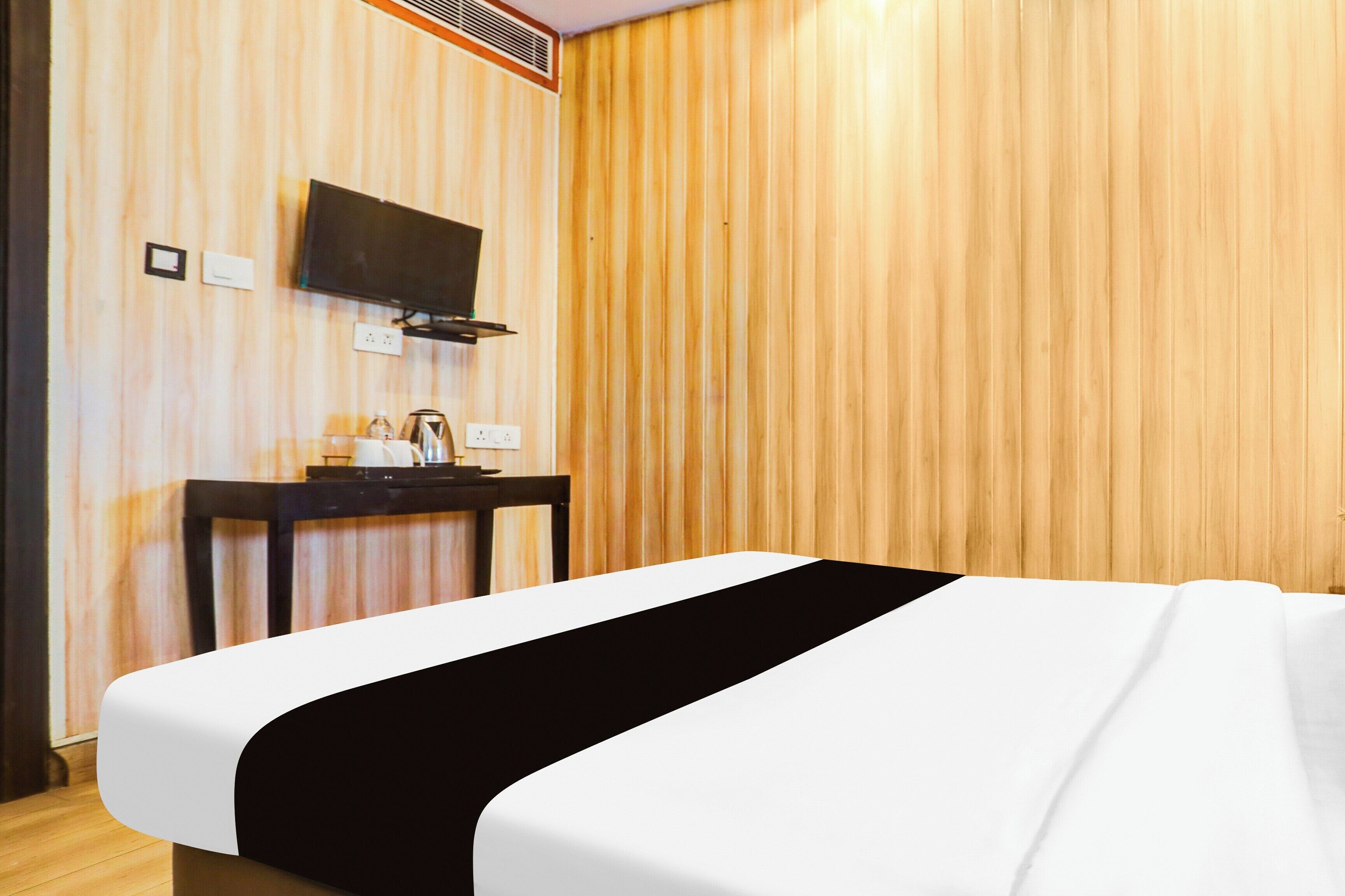 Une chambre d’hôtel avec un lit, un bureau avec une télévision et un radiateur fixé au mur.