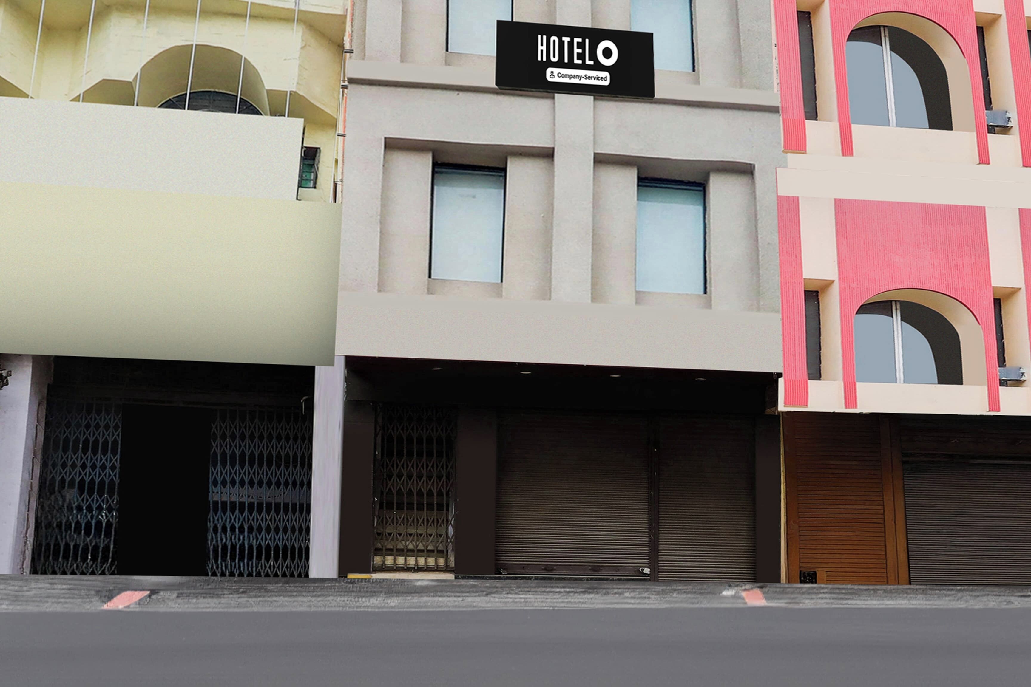 Un bâtiment d’hôtel avec une enseigne indiquant : « HOTELO Company Serviced ».