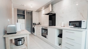 A modern kitchen with a built-in oven, microwave, and a small dining area with a toaster. - Free Parking 2BR Sleeps 5 Close to JR Hospital (Oxford)