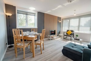 A modern living room with a dining area, a fireplace, and a sofa. - Free Parking 2BR Sleeps 5 Close to JR Hospital (Oxford)