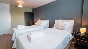 A hotel room with two beds, a wardrobe, a desk with a lamp, and a wall clock. - Free Parking 2BR Sleeps 5 Close to JR Hospital (Oxford)