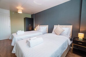 Ein Hotelzimmer mit zwei Betten, einem Kleiderschrank, einem Schreibtisch mit Lampe und einer Wanduhr.