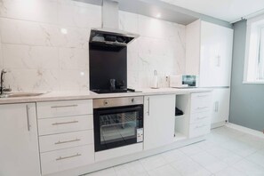 Une cuisine moderne équipée d’un four encastré, d’un four à micro-ondes et d’une cuisinière à gaz.