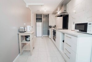 A modern kitchen with white cabinetry, a built-in oven, a microwave, and a coffee maker. - Free Parking 2BR Sleeps 5 Close to JR Hospital (Oxford)