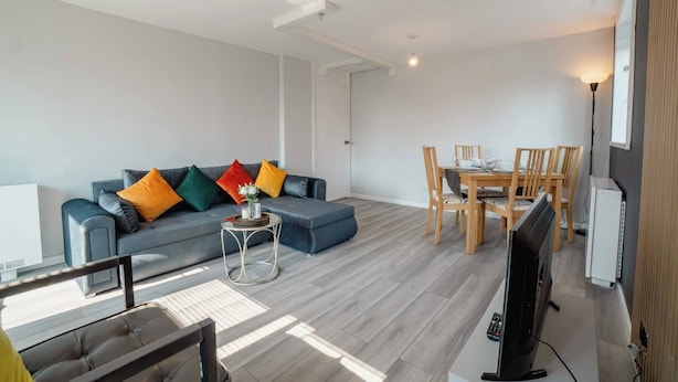 A modern living room with a sofa, a dining table with chairs, a TV, and a small side table. - Free Parking 2BR Sleeps 5 Close to JR Hospital (Oxford)