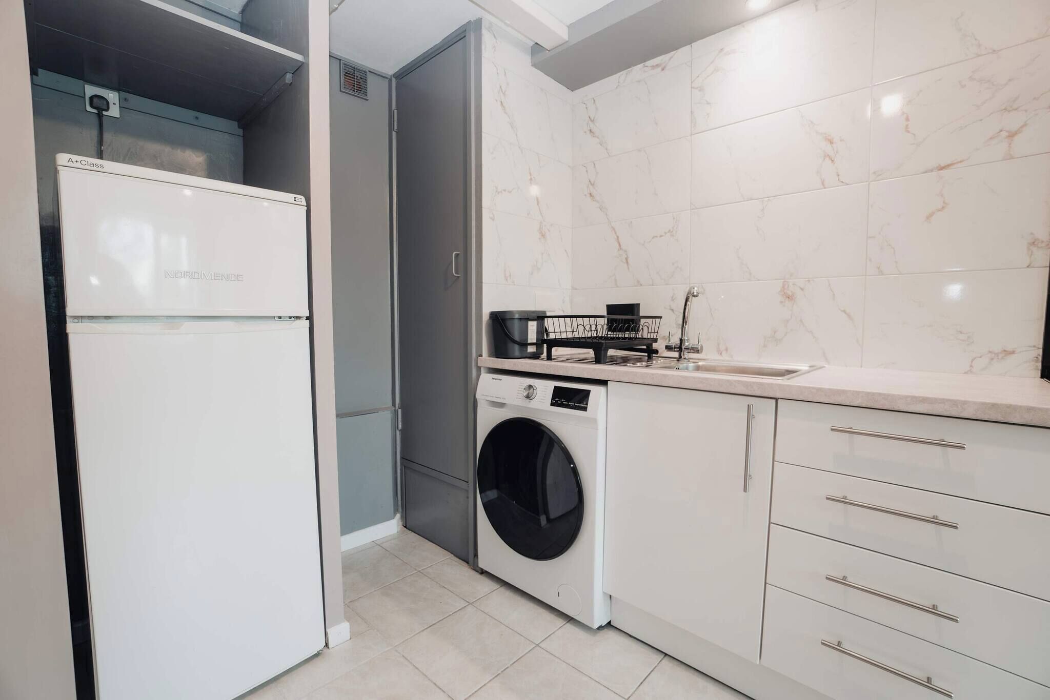 Cocina compacta con lavadora, lavaplatos y refrigerador.