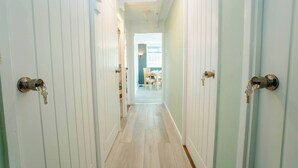 A hallway with white doors, a wooden floor, and a view into a dining area with a table and chairs. - Free Parking 2BR Sleeps 5 Close to JR Hospital (Oxford)