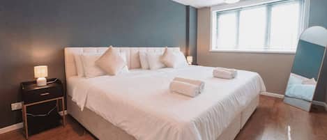 Une chambre d’hôtel avec un grand lit, des tables de chevet, une fenêtre avec des stores et un miroir.