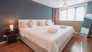A hotel room with a large bed, bedside tables, a window with blinds, and a mirror. - Free Parking 2BR Sleeps 5 Close to JR Hospital (Oxford)