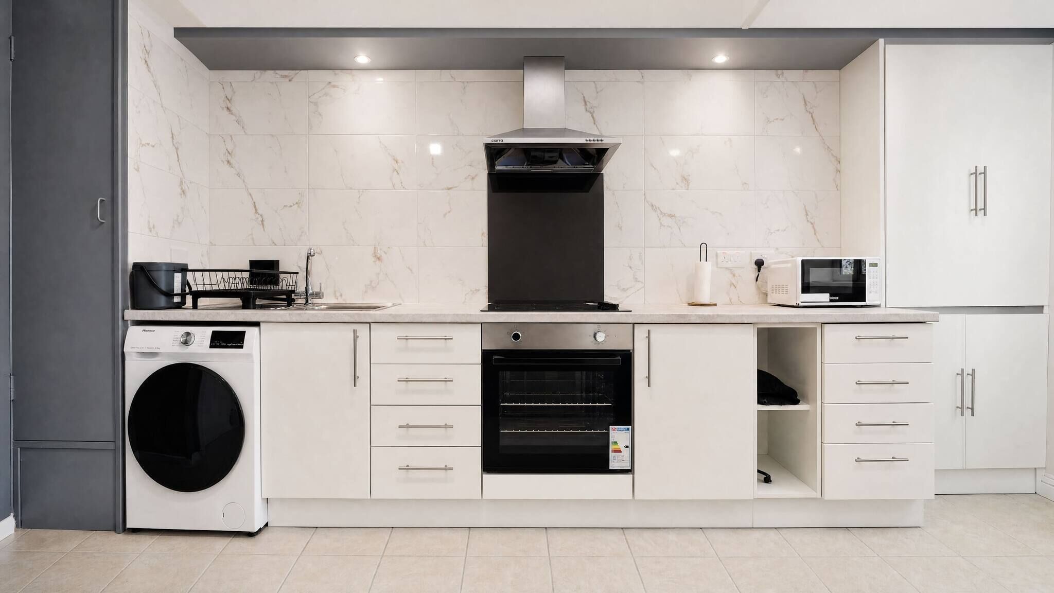 A modern kitchen with a built-in washer, oven, microwave, and a compact dishwasher.
