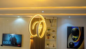 Un interior moderno con una lámpara circular, un televisor de pantalla plana y un estante de pared con objetos decorativos.
